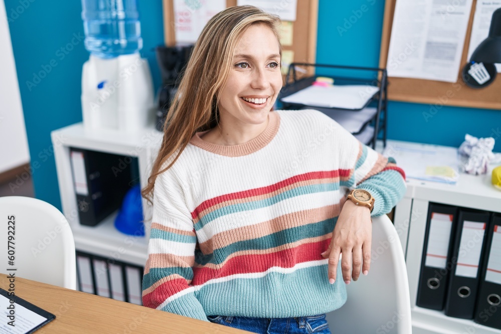 Obraz premium Young blonde woman business worker smiling confident sitting on table at office