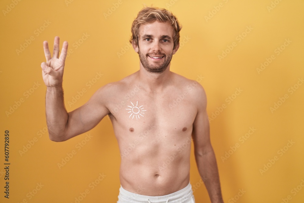Caucasian man standing shirtless wearing sun screen showing and pointing up with fingers number three while smiling confident and happy.
