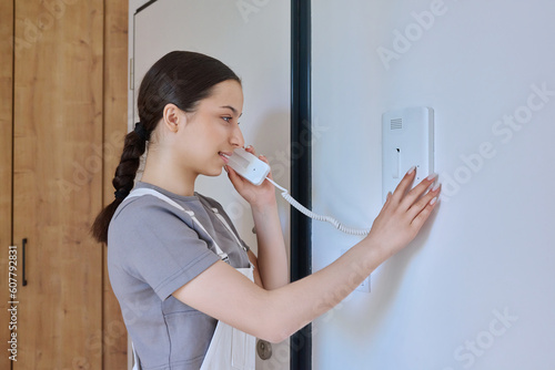 Φωτογραφία Teenage girl holding intercom handset while talking to guest