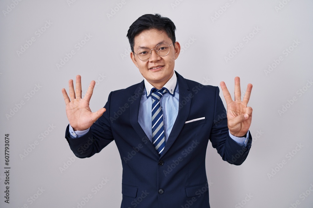 Young asian man wearing business suit and tie showing and pointing up with fingers number eight while smiling confident and happy. Young asian man wearing business suit and tie showing and pointing up with fingers number eight while smiling confident and happy.