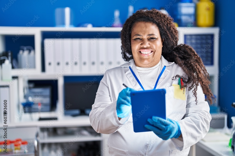 African american woman scientist smiling confident writing on touchpad at laboratory African american woman scientist smiling confident writing on touchpad at laboratory