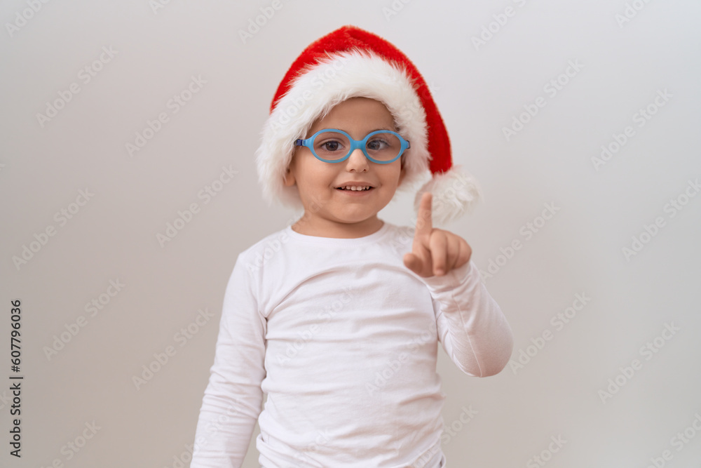 Little hispanic boy wearing glasses and christmas hat smiling with an idea or question pointing finger with happy face, number one Little hispanic boy wearing glasses and christmas hat smiling with an idea or question pointing finger with happy face, number one