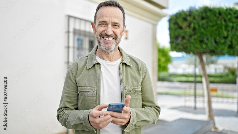 Middle age man smiling confident using smartphone at street Middle age man smiling confident using smartphone at street
