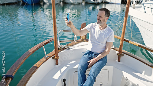 Middle age man make selfie by smartphone sitting on boat at port