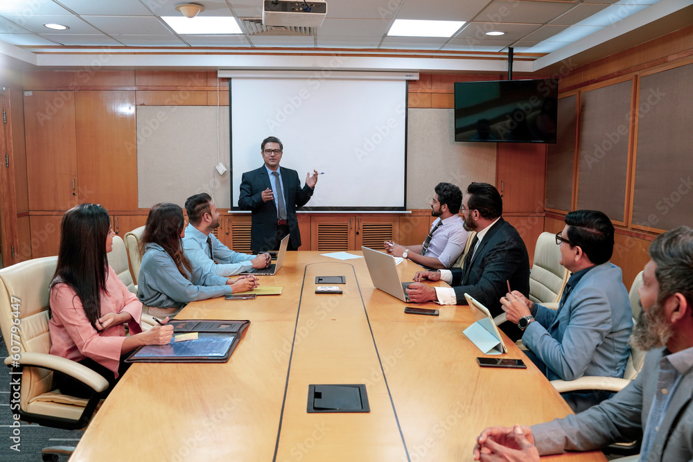 Indian business coach giving training to employees group at meting hall Indian business coach giving training to employees group at meting hall