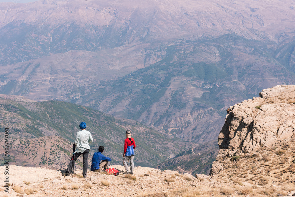 Tourists and hikers enjoying the view of highlands of Iran in the mid day sun, peaks, no vegetation, mountain chain, Alborz mountain range  