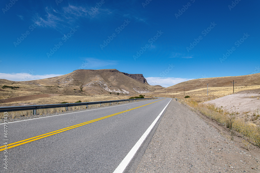lonely and quiet road that runs through the arid desert under a blue sky on a very hot day