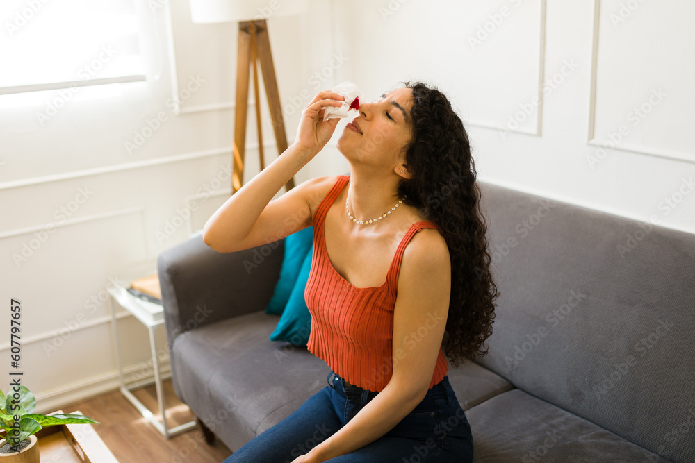 Sick young woman with a bleeding nose resting on the couch Sick young woman with a bleeding nose resting on the couch