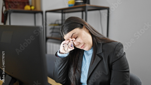 Young hispanic woman business worker stressed using laptop taking glasses off at office