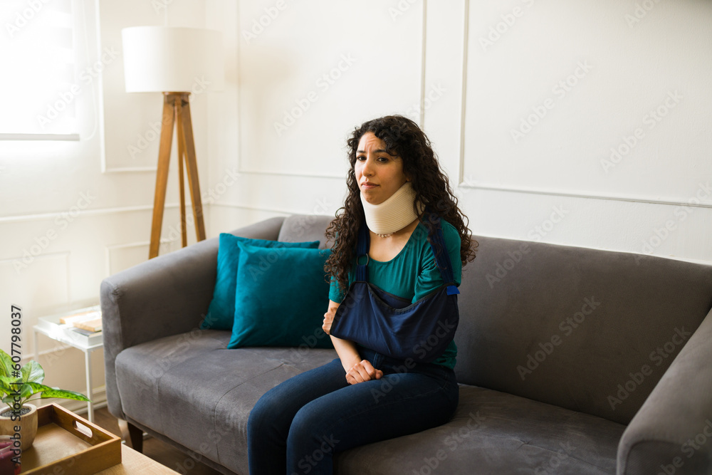 Injured woman with a broken arm using a neck brace at home Injured woman with a broken arm using a neck brace at home