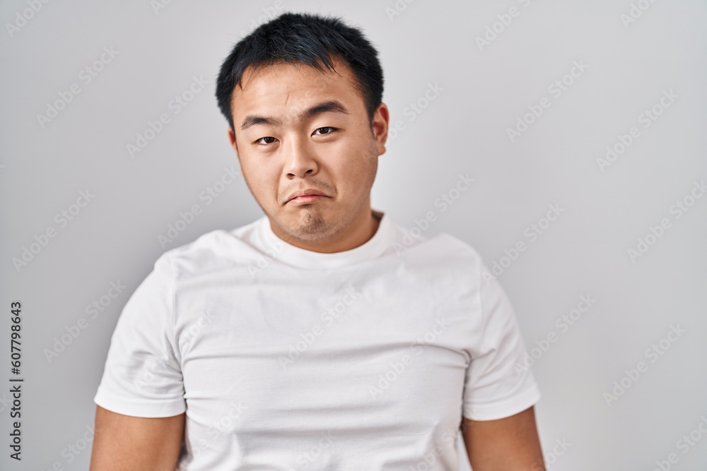 Young chinese man standing over white background depressed and worry for distress, crying angry and afraid. sad expression. Young chinese man standing over white background depressed and worry for distress, crying angry and afraid. sad expression.