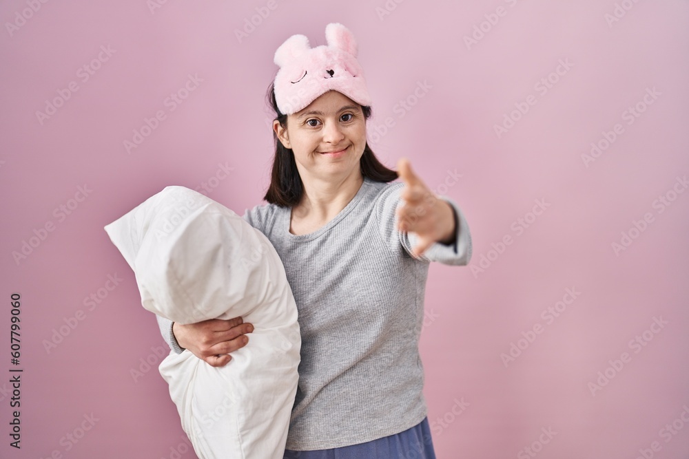 Woman with down syndrome wearing sleeping mask hugging pillow smiling friendly offering handshake as greeting and welcoming. successful business. Woman with down syndrome wearing sleeping mask hugging pillow smiling friendly offering handshake as greeting and welcoming. successful business.