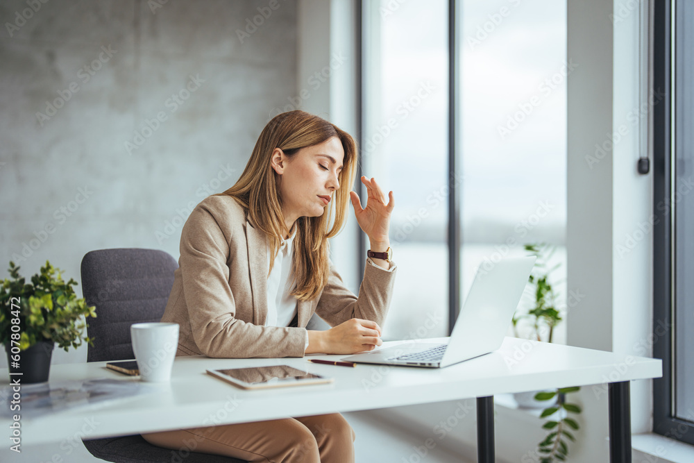 Female entrepreneur with headache sitting at desk. Businesswoman under terrible physical tension at work. Business woman with hands on her face looking exhausted Female entrepreneur with headache sitting at desk. Businesswoman under terrible physical tension at work. Business woman with hands on her face looking exhausted