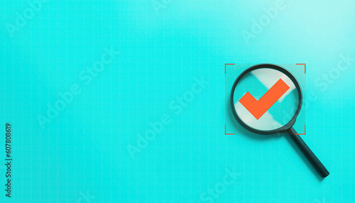 Hand hold magnifying glass focusing on right choice checkmark on blue background. Sign and symbol concept.