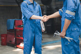 Two professional auto mechanics shaking hands, all kinds of car specialists, expert auto repair and standard auto repair center.