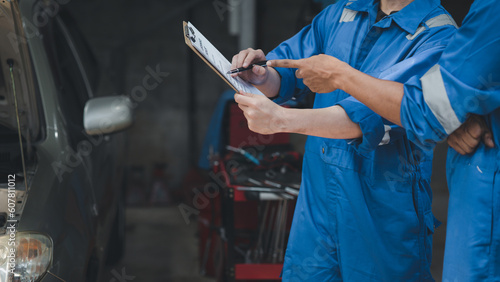 Two professional car mechanics looking at car inspection papers together, all types of car specialists, expert car repairs and certified auto repair centers.