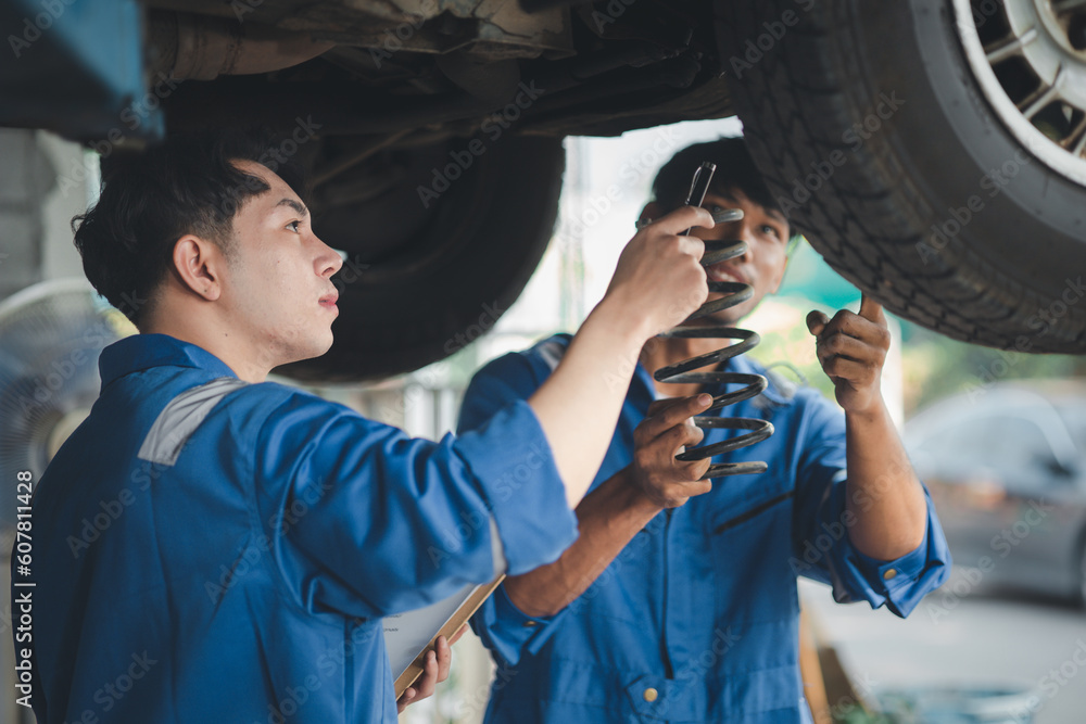 Two professional car mechanics helping to repair shock absorbers and car suspension, all kinds of car experts, expert auto repair and accredited auto repair center. Two professional car mechanics helping to repair shock absorbers and car suspension, all kinds of car experts, expert auto repair and accredited auto repair center.