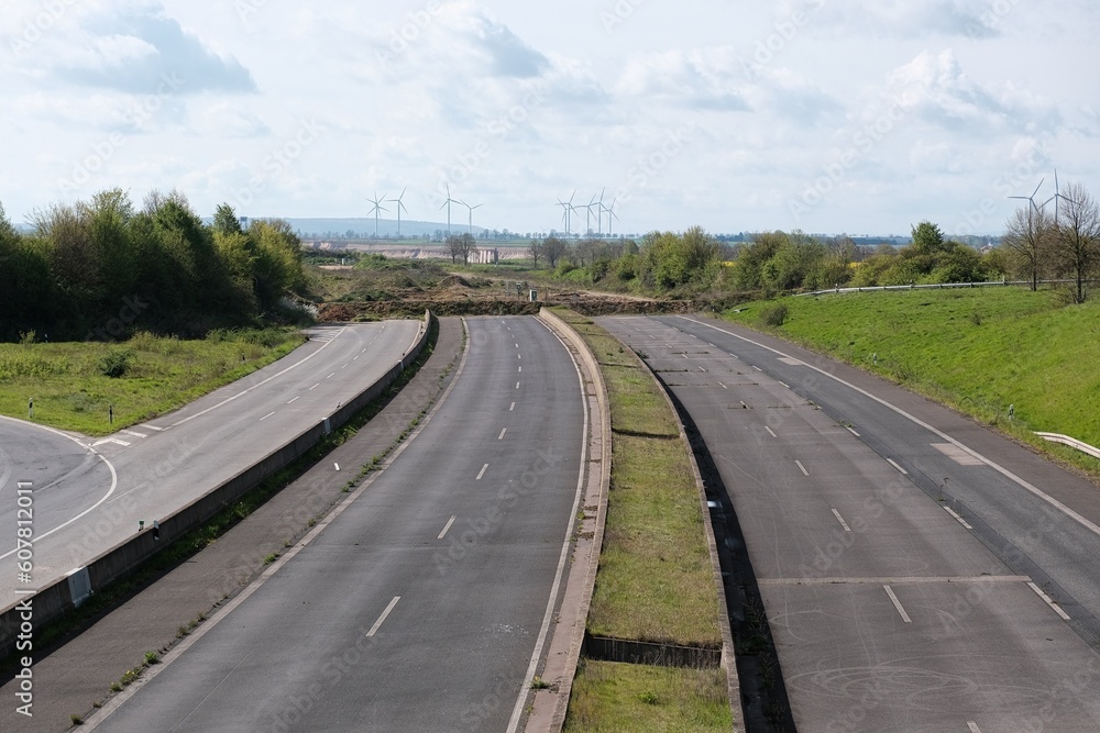 Ende einer Autobahn mit Windräder am Horizont Ende einer Autobahn mit Windräder am Horizont