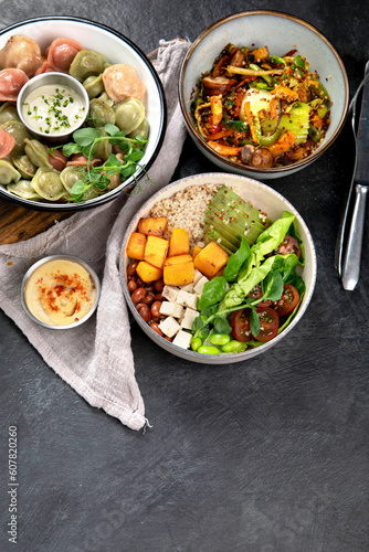 Vegetarian and various vegan dishes on dark table.