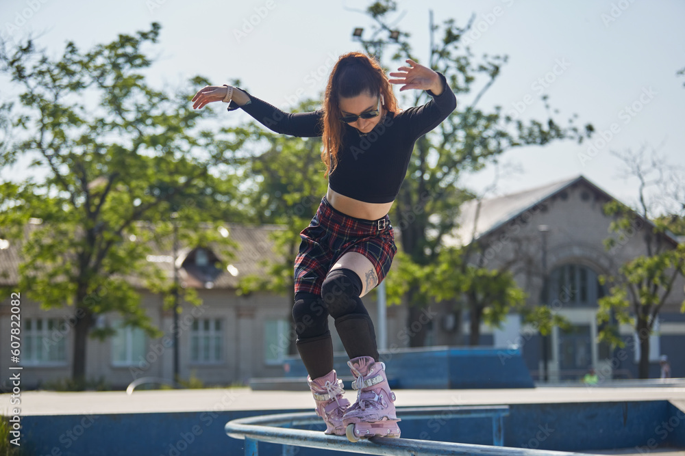 Cool young roller blader female grinding on a rail in a skatepark