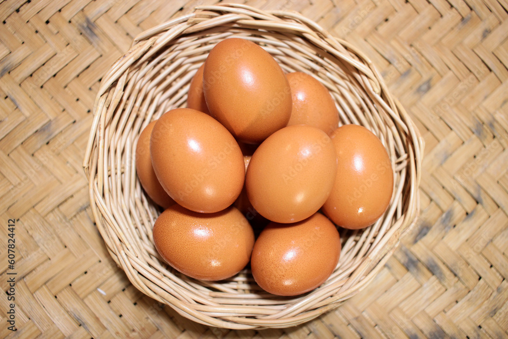 Close-up view of raw chicken eggs in egg basket on brown wooden background Close-up view of raw chicken eggs in egg basket on brown wooden background