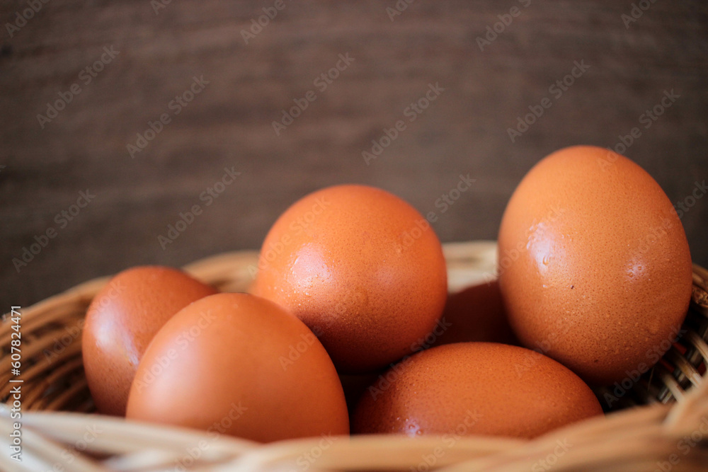 Close-up view of raw chicken eggs in egg basket on brown wooden background Close-up view of raw chicken eggs in egg basket on brown wooden background
