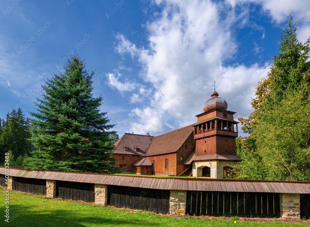 Wooden evangelical articular church of the Svaty Kriz(Holy Cross), is one of the largest wooden churches in Europe.Green meadow, flowering dandelion, old architecture. Paludza, Svaty Kriz, 