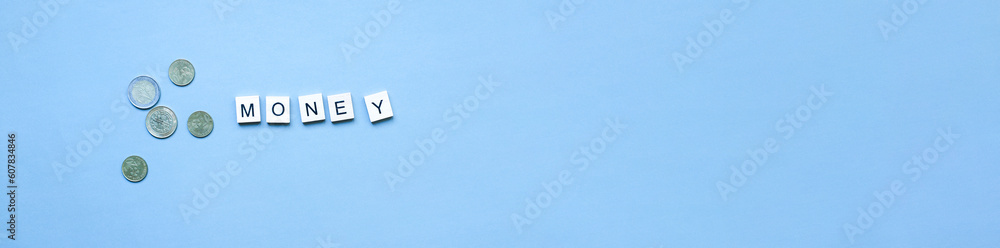 Banner The word money from wooden letters. Flat lay coins on blue background Banner The word money from wooden letters. Flat lay coins on blue background