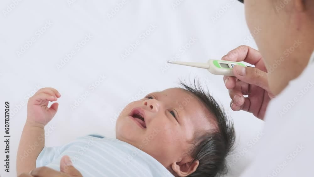 Little baby lay crying from a fever while her mother hold thermometer