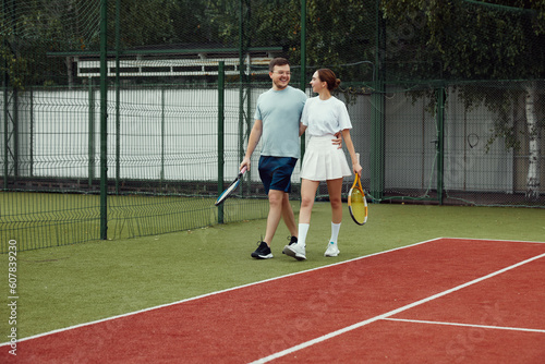 Young couple on tennis court. Two tennis players are smiling and walking around the court and talking