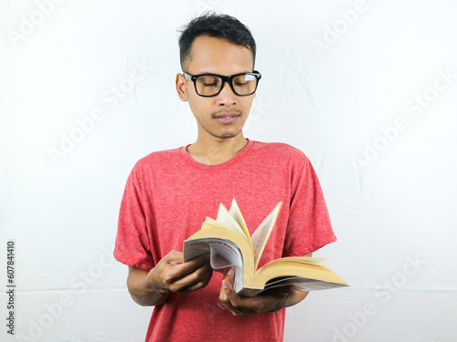 portrait of asian man holding book with reading focused expression. photo