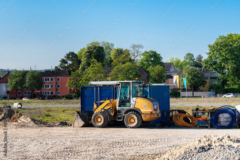 Construction site with a yellow wheeled bulldozer standing on it and folded cables.