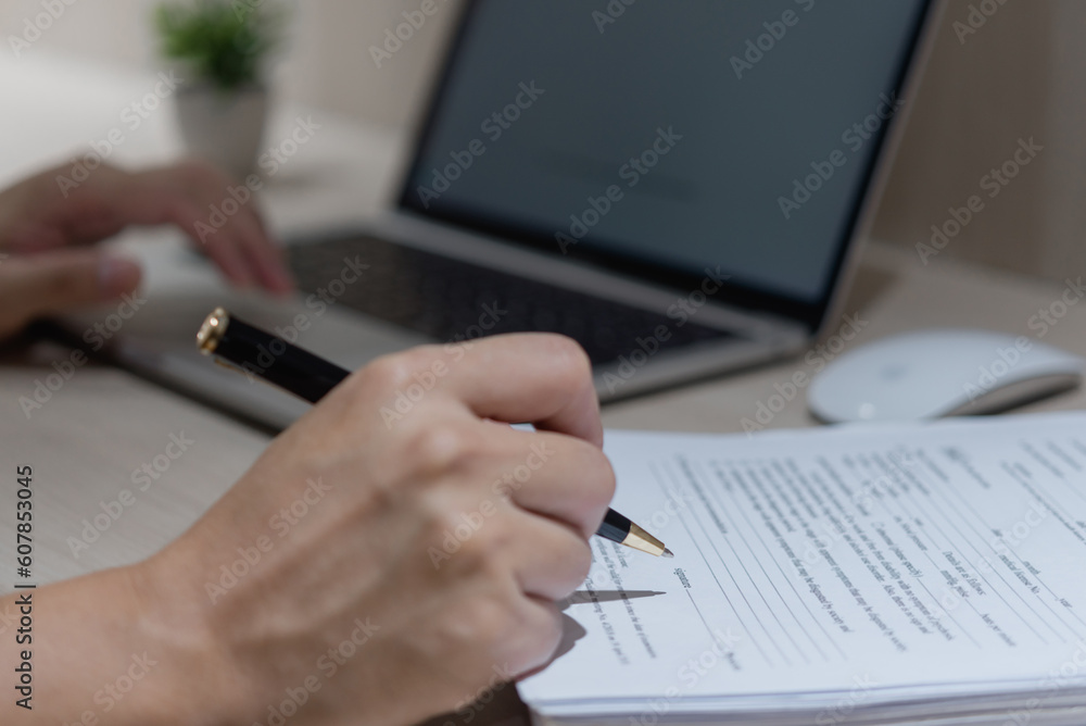 Hand using writing pen with paperwork in business company personal information or signature job application documents on desk. Hand using writing pen with paperwork in business company personal information or signature job application documents on desk.
