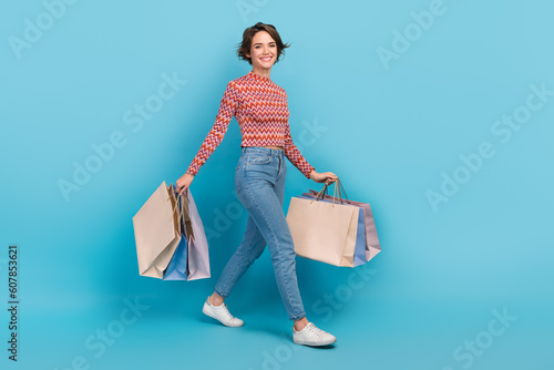 Photographie Full length photo of excited shiny lady wear striped top walking holding shopper