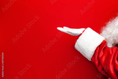 empty hand of santa claus in gloves holding empty space on red background, santa holding copy space photo