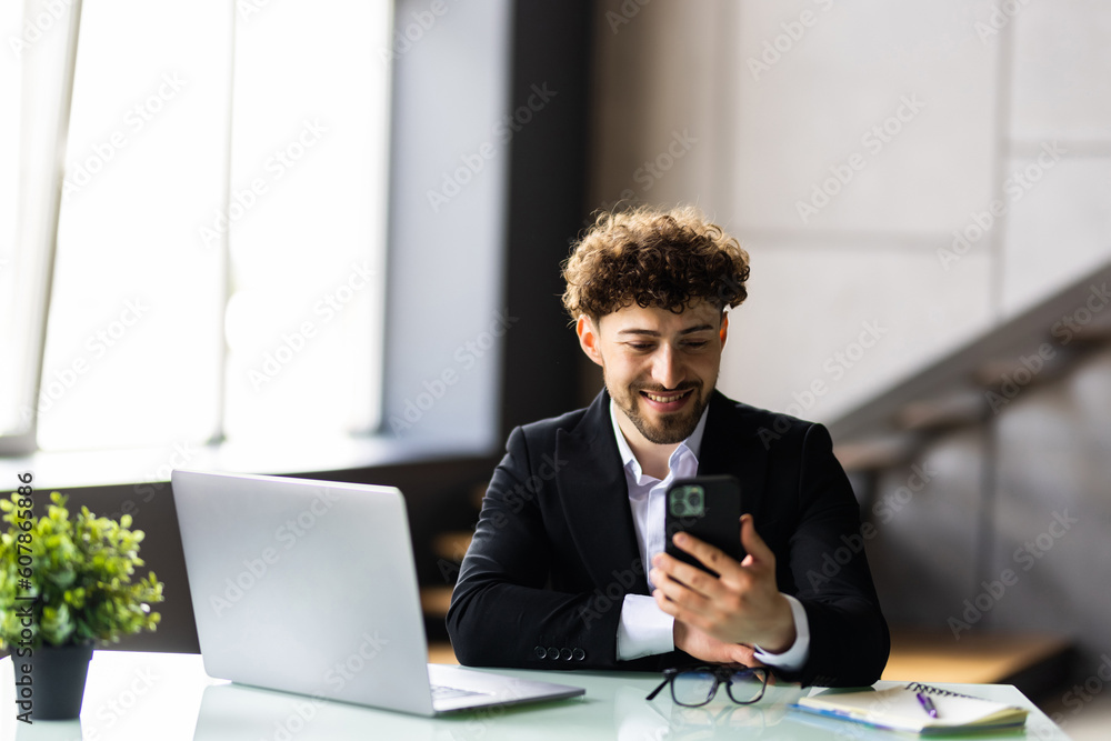 Young business man working at home with laptop and uses a smartphone in office Young business man working at home with laptop and uses a smartphone in office