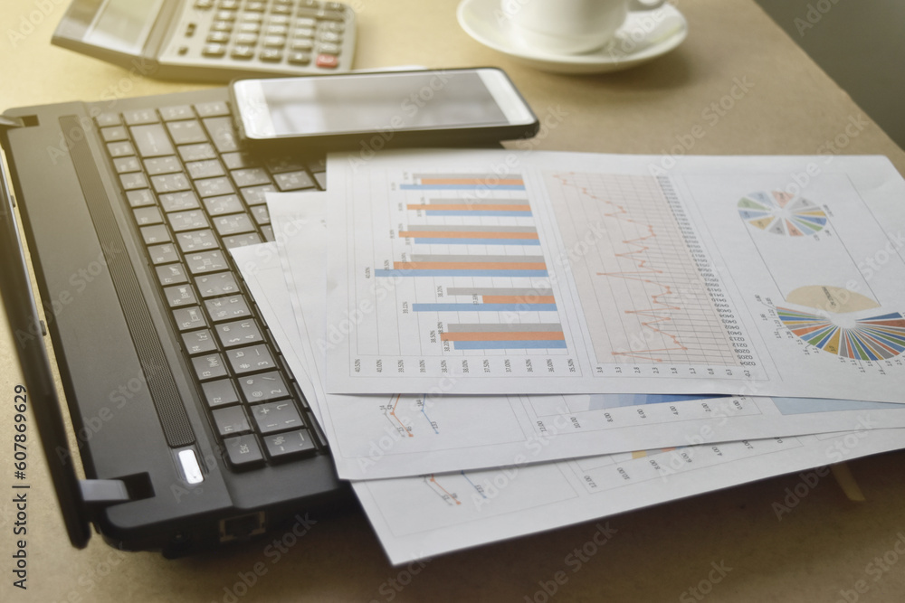 Obraz premium graphs and charts. business reports and pile of documents with a coffee cup, glasses, smartphone, calculator place on desk.