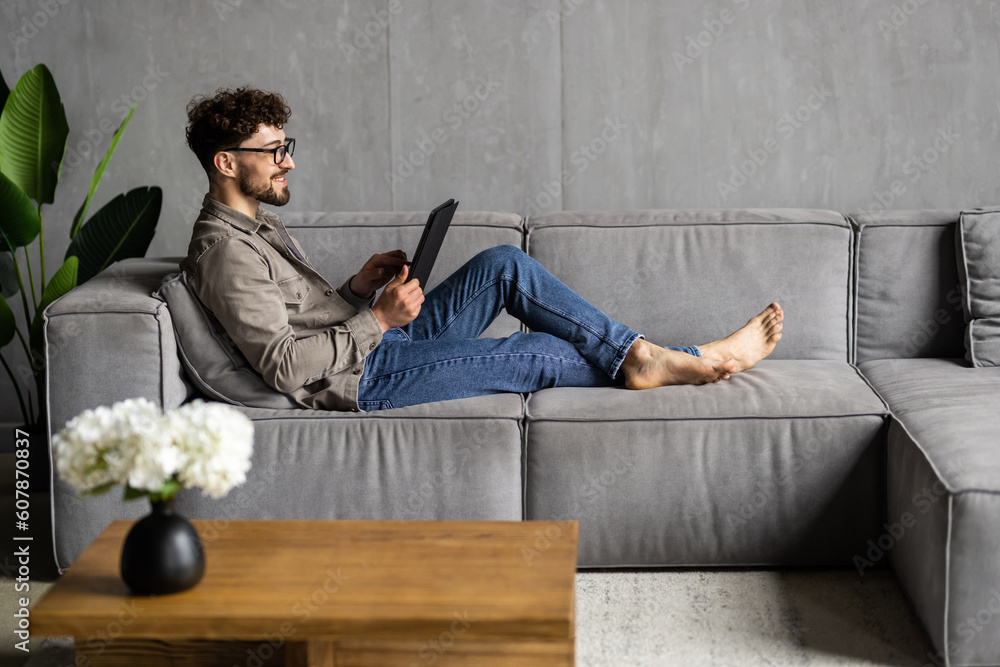 Portrait of a casual man lying on the sofa with tablet