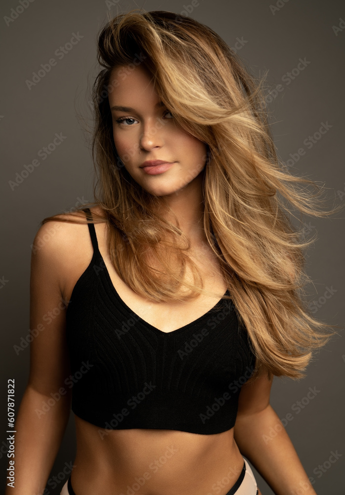 Fototapeta premium Happy blonde young girl in beautiful outfit standing on grey background. 