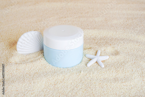 Cosmetic cream in blue bottle with Starfish on the sand background, copy space. UVA and UVB protection. Summer cosmetics