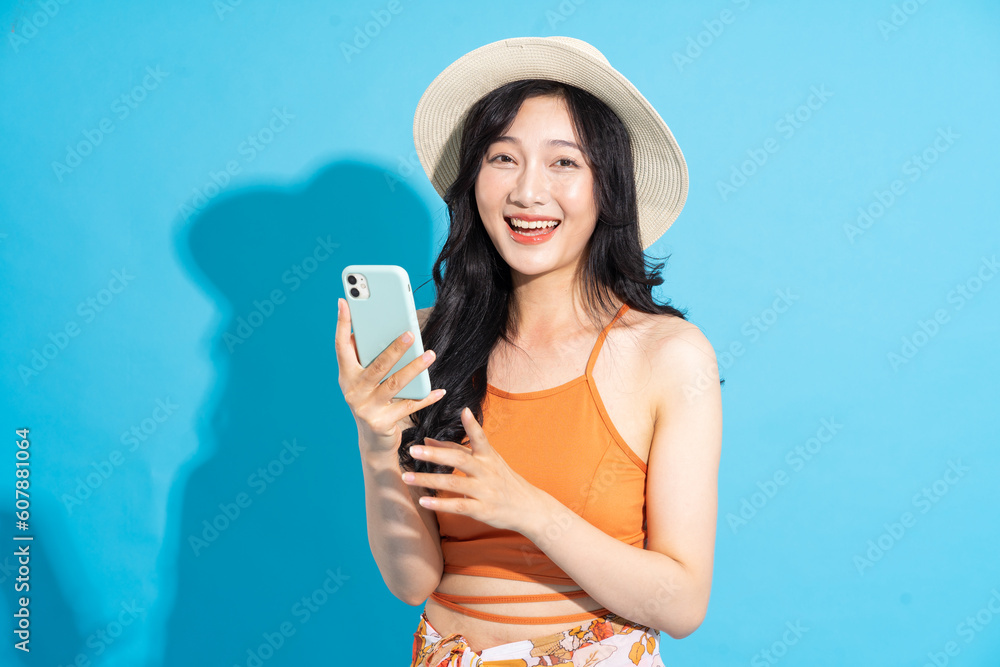 Portrait of a beautiful asian girl in a swimsuit smiling happily on a blue background Portrait of a beautiful asian girl in a swimsuit smiling happily on a blue background