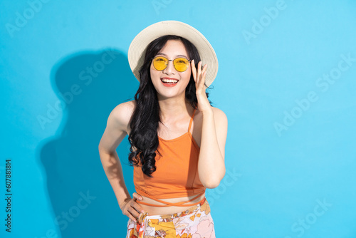 Portrait of a beautiful asian girl in a swimsuit smiling happily on a blue background