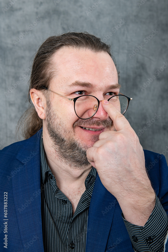 Fototapeta premium One man in a blue jacket adjusts his glasses