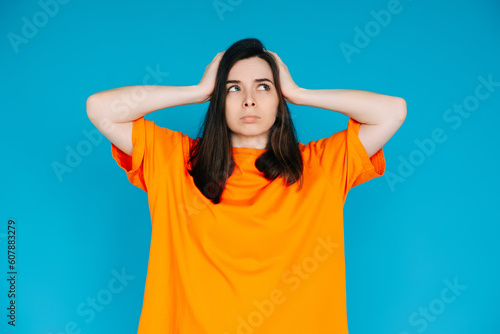 Stressed Young Woman Expressing Discontent, Touching Head - Negative Emotions, Frustration, Isolated Blue Background © Yauhen