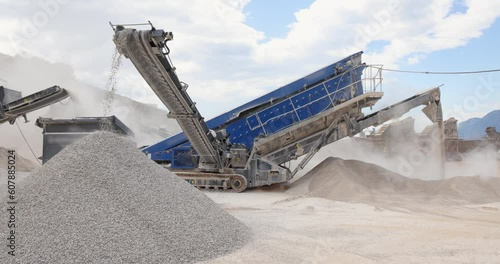 Stone crushing machine at open pit mining and processing plant for crushed stone. Piles of gravel stone and conveyor belts on the side of the road photo