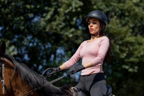 Female rider with helmet riding a horse in an equestrian center