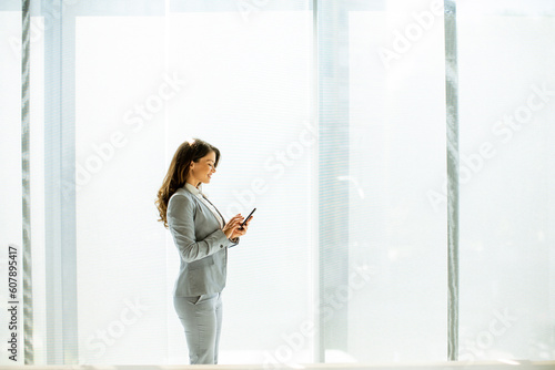 Young woman using mobile phone by the office window