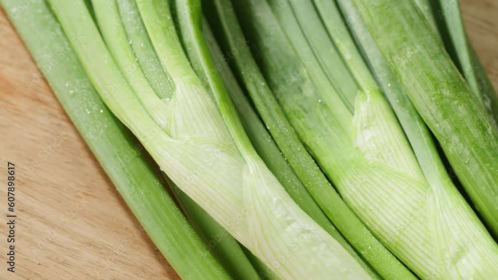 Bunch of green onion feathers with drops of water on a cutting board, Close-up macro rotating shot. Bunch of green onion feathers with drops of water on a cutting board, Close-up macro rotating shot.
