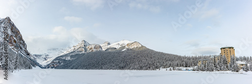 Incredible Lake Louise during winter time with scenic  landscape in panorama, panoramic view with snow covering the frozen lake area.  photo