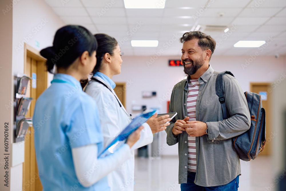 Happy man talks to female doctor in hallway of medical clinic. Happy man talks to female doctor in hallway of medical clinic.